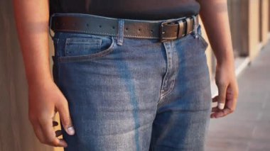 Kot pantolon ve siyah kemer giyen bir adam.,