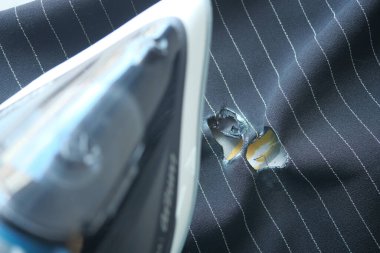 Yakınına ütü yerleştirilmiş hasarlı bir kumaş parçasının detaylı bir yakın görüntüsü.