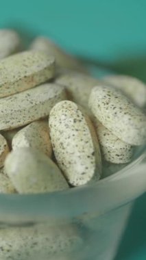 Cam bir kasede sergilenen bitkisel tabletler, güzel bir sunum için yeşil yapraklarla tamamlanmış.