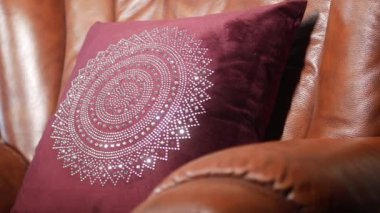 Şık ve zarif bir bordo yastık. Lüks bir deri sandalyede karmaşık bir tasarım sunuyor.