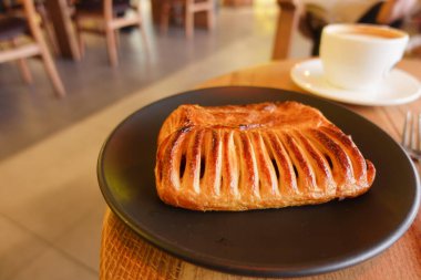 Sıcak bir kafein atmosferinde bir fincan kahveyle servis edilen taze pişmiş hamur işi.