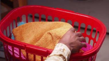 Çamaşır sepetine havlu koyan biri..