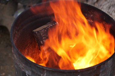 Şiddetli alevler metal bir fıçının içindeki kuru odunları hararetle tüketiyor.