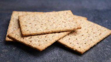 Karanlık bir yüzeyde lezzetli çıtır çıtır tahıllı krakerler duruyor. Atıştırmak için birebir.