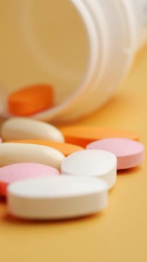 Bir şişeden yüzeye dökülen vitamin ve ilaçlardan oluşan renkli bir karışım.