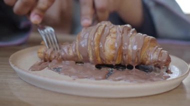 Çikolatalı kruvasan yiyen biri.,