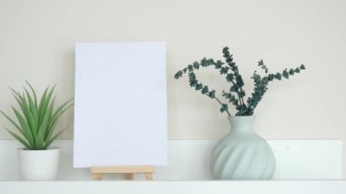 Zarif, basit bir dekor. Taze ve canlı bitkilerle eşleştirilmiş boş bir tuval sergiliyor.