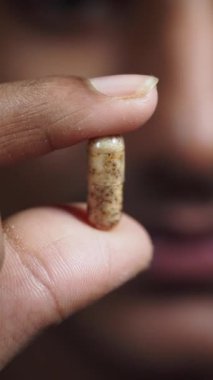 Dokulu bir yüzeye sahip eşsiz bir kapsülü sıkıca tutan bir elin yakın çekim görüntüsü