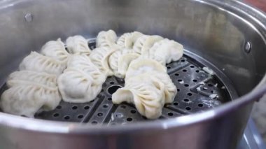 Buharda pişmiş hamur köfteleri, güzel bir şekilde metal bir sepetin içinde, sıcak servis edilmeye hazır.