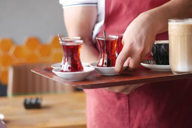 Garson kafede bir tepside çay ve kahve taşır.