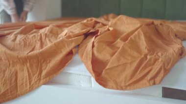 Buruşuk turuncu yatak örtüsü. Sıcak bir yatak örtüsü. Sıcak, davetkar bir ortam yaratıyor.