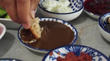 Ekmeği çeşitli sosların arasına daldıran bir el..