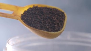 Tahta kaşık taze öğütülmüş kahveyi cam kavanoza dolduruyor..