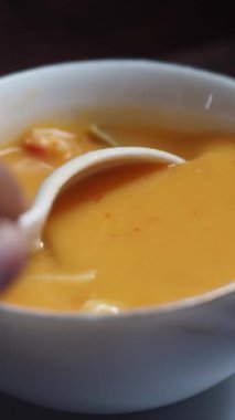 Kalın, kremalı bir çorba, beyaz bir kâsede kaşıkla yavaşça karıştırılıyor.