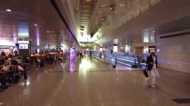 Gezginlerin ve aydınlatılmış yürüyüş yollarının yer aldığı modern havaalanı içi.