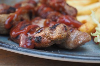 Kızartma ve yapraklı salatanın yanında ketçaplı ızgara et.,