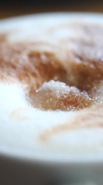 Beyaz şeker kahve fincanındaki kağıt bir paketten dökülüyor. .