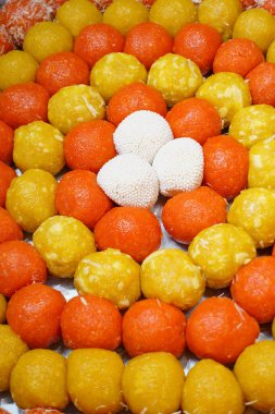 Yerel bir festivalde turuncu, sarı ve beyaz renkli geleneksel şekerlerin geniş bir düzenlenmesi sergilendi. Tadını çıkarmak için çeşitli tatlar ve dokular içeriyor..