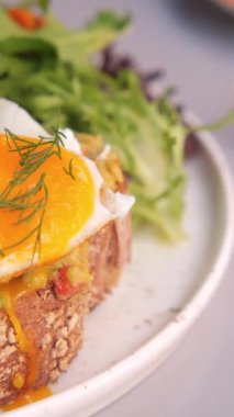 Taze yeşilliklerle birlikte mükemmel haşlanmış yumurtanın sergilendiği lezzetli bir brunch tabağının tadını çıkarın..