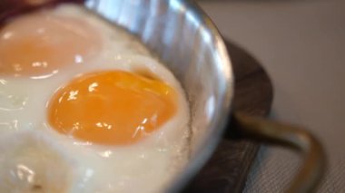 Güneşli tarafı yumurta pişirme sürecini izleyin. Sıcak bir mutfakta parlak sarıları ve cızırtılı sesleri gösterin..