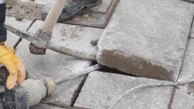 İşçiler büyük bir taş levhayı dikkatle kaldırmak ve manipüle etmek için makineler kullanıyorlar. Dekor, takım çalışmasını ve hassasiyetini gösteren bir açık hava inşaat alanı gibi görünüyor..