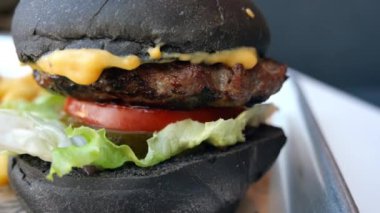 Lezzetli bir köfte, taze sebze ve erimiş peynirin yer aldığı lezzetli bir kara hamburgeri deneyin. Enerji dolu canlı bir yiyecek piyasasında servis edilir..