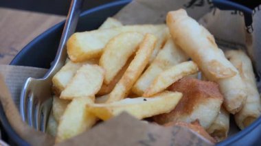 Siyah bir kasede sunulan taze kızarmış patatesler altın rengi ve dokusunu gözler önüne seriyor. Keyifli bir atıştırma deneyimi için çeşitli soslarla mükemmel eşleştirilmiş..