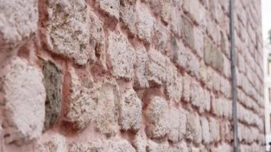 Sağlam taş duvar, eski bir bölgedeki sessiz bir caddenin arka planına dayanan rustik dokuyu ve tarihi sergiliyor. Bu duvar mahalleye karakter katıyor..