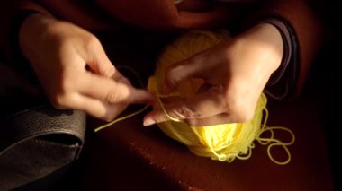 Parlak sarı iplikle ustalıkla çalışan ellerin yakın görüntüsü karmaşık desenler yaratıyor. Dekor, sanatsal süreci geliştiren rahat bir atmosferi vurguluyor..