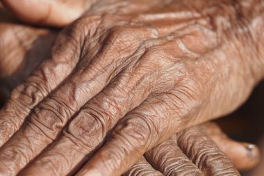 Kırışık eller nazikçe dinleniyor, hayat tecrübeleri ve hikayeleri vurguluyor..