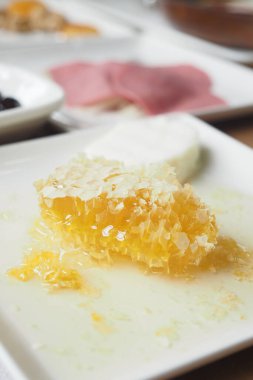 Süt ürünleri ve et seçimleriyle servis edilen taze bal peteği.