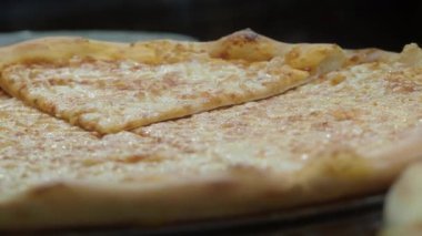 Lezzetli peynirli pizza dilimleniyor ve sıcak servis ediliyor..