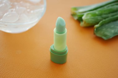 Aloe vera yaprakları ve buz küplerinin yanında taze yeşil dudak kremi..