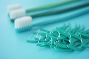 Turkuaz arka planda çeşitli diş bakımı araçları.