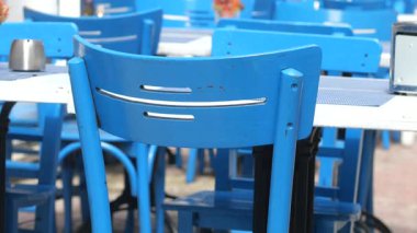 Canlı bir restoranın dışındaki masalara dizilmiş renkli mavi sandalyeler..