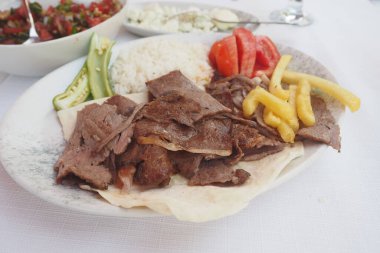 Kuzu çeviren kebap, pirinç ve patates kızartması tabakta. ,