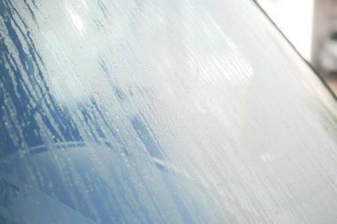 Serin bir sabahta arabanın ön camına su damlacıkları yapışır..