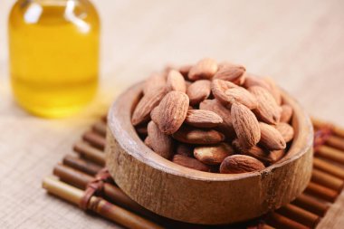 Doğal bademler küçük bir yağ şişesinin yanında bir kasede sergilenir..