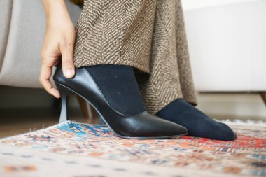 Bir insan otururken zarif siyah topukluları dikkatlice giyer..