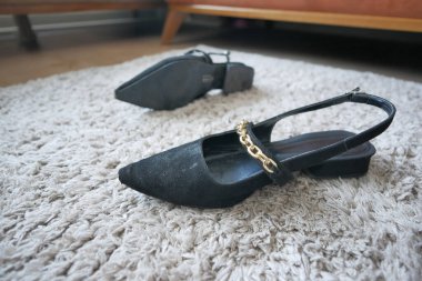 İki çift siyah sapan ayakkabısı yumuşak, desenli bir halıda dinleniyor..