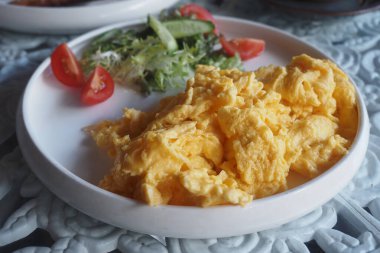 Çırpılmış yumurta, domates ve yeşilliklerin yanında kaplıdır..