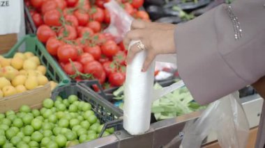 Alışveriş yapan kişi canlı pazarlardan taze meyve ve sebze topluyor..
