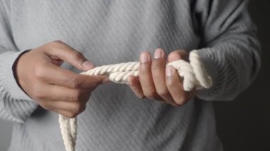 Eller farklı düğüm tekniklerini göstermek için ipi ustalıkla manipüle eder.