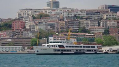 İstanbul 'da arkaplan olarak binalar bulunan bir feribot sularda geziniyor.