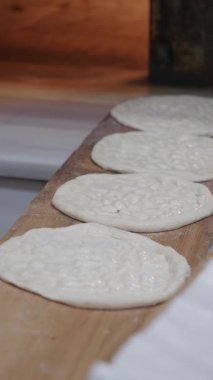 Hamur mermileri ahşap bir tahtanın üzerinde şekilleniyor, pişirilmeye hazır..