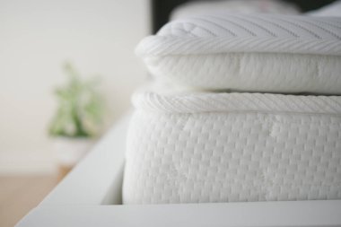 Yumuşak beyaz yataklar çağdaş bir yatak çerçevesinde düzgünce düzenlenir..