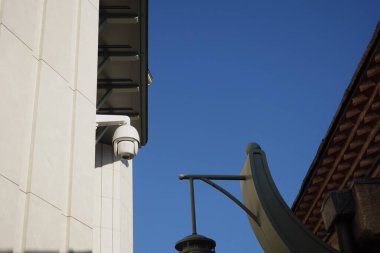 Beyaz bir duvara parlak bir gökyüzüne karşı bir güvenlik kamerası monte edilmiştir..