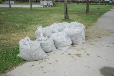Bir sürü çöp torbası park kaldırımında sıraya dizilmiş..