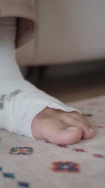 Bandajlı ayak rengarenk bir halıya nazikçe dayanır..