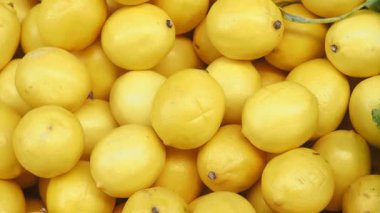 Parlak sarı limonlar kalabalık bir pazara yığılmış, alıcıları davet ediyorlar..